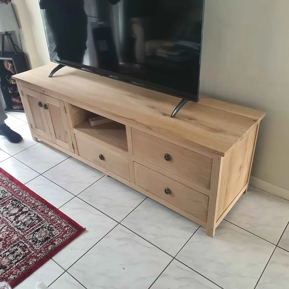Solid wood TV stand with drawers and an open shelf, installed in a lounge under a TV
