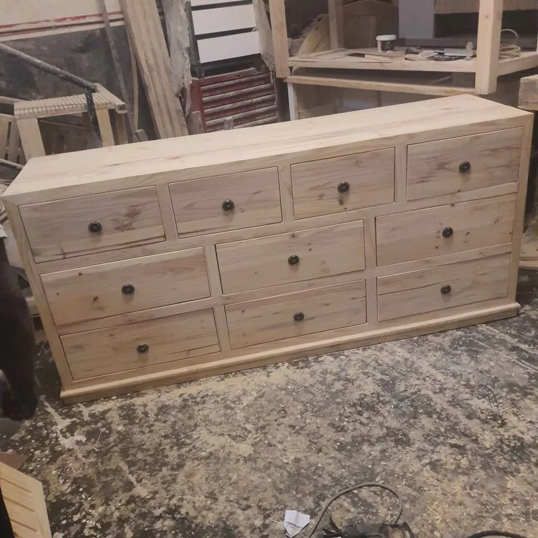 A long solid wood dresser with rows of drawers in the workshop